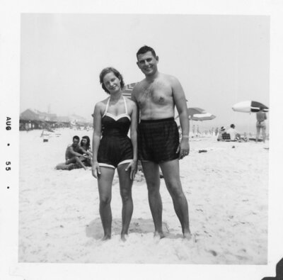 Vintage photo of couple standing on beach wearing bathing suits and looking at the camera