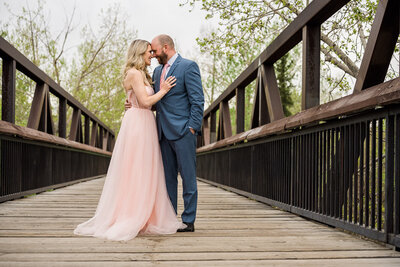 A well dressed couple at their engagement session. Woman wearing pink dress while her fiance wore a grey suit in Edmonton, Alberta