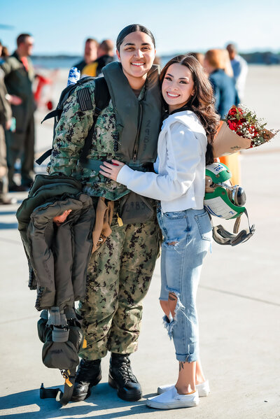 A sailor and her wife smile for a picture during their homecoming at Norfolk Naval Station.