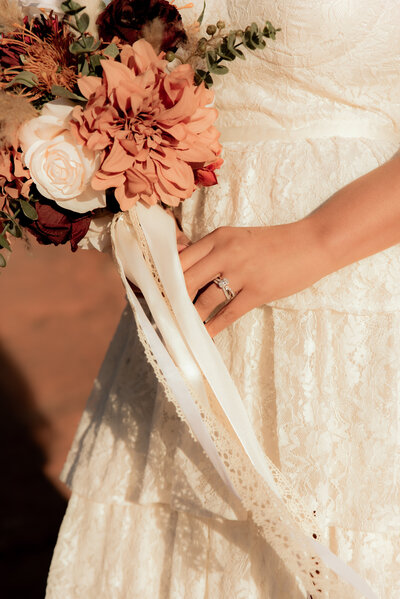 Bride holding bouquet of flowers. Camera is focused on her ring. 