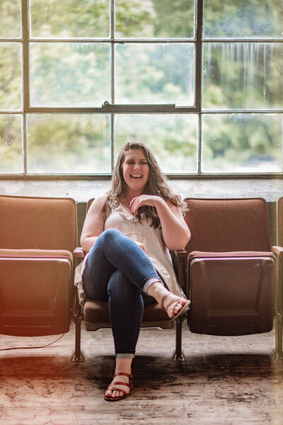 Founder of Hatched Design Co, Kelbey McGhee, sitting in theater chairs laughing