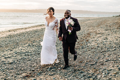 interracial wedding couple walk across beach