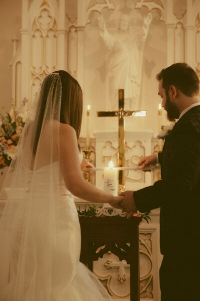 Bride and groom at the altar lighting their unity candle during their ceremony in Brenham, Texas