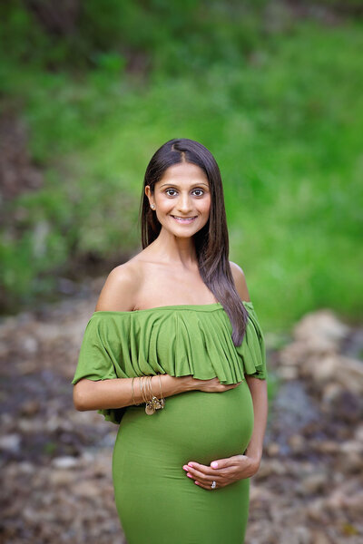 new jersey expecting mom posing in the park wearing a green dress