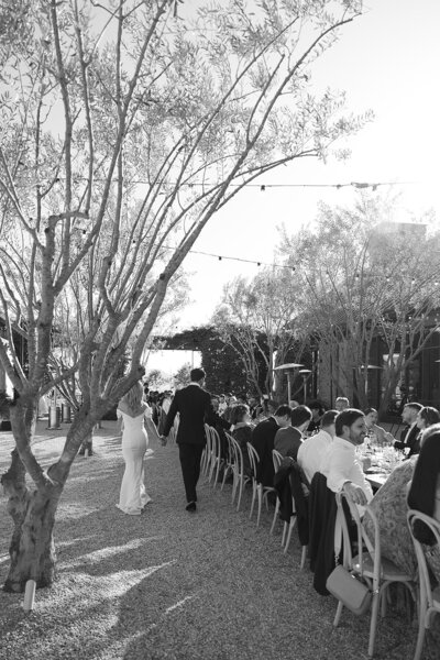 Reception photo of bride and groom walking along guest tables in Santa Ynez, California