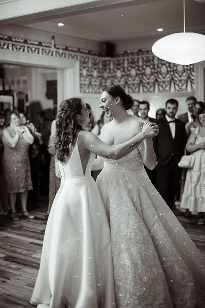 Brides smiling while doing their first dance