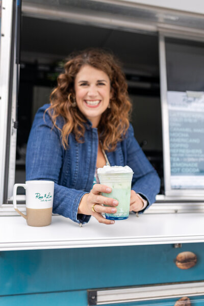 Rachel smiling while holding a drink out of the coffee truck serving window
