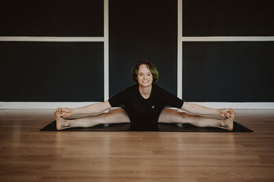 A person sitting on a yoga mat stretching 