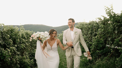 Bride and groom hold hands walking through Veritas Vineyards in Charlottesville