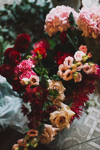 Lush arrangement of red, pink, and cream flowers in a moody setting