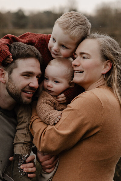knuffelend gezin tijdens een outdoor fotoshoot in de natuur te Bonheiden.
