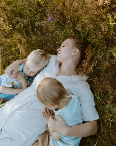 A mother and her sons laying down on the ground  at a park in Käpylä in Helsinki