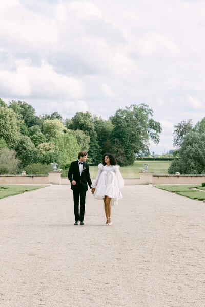 a picture of the married couple walking hand in hand down a gravel path at chateau du grand luce