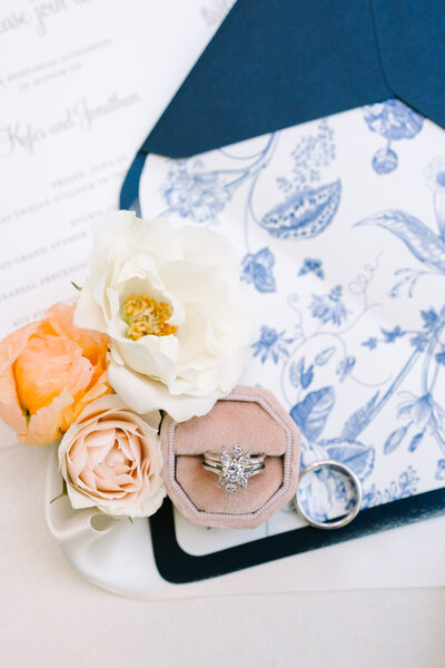 flat lay of wedding rings with peach flowers