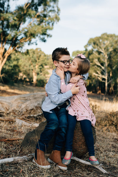 pregnant women wearing red maternity dress being embraces by husband's arms