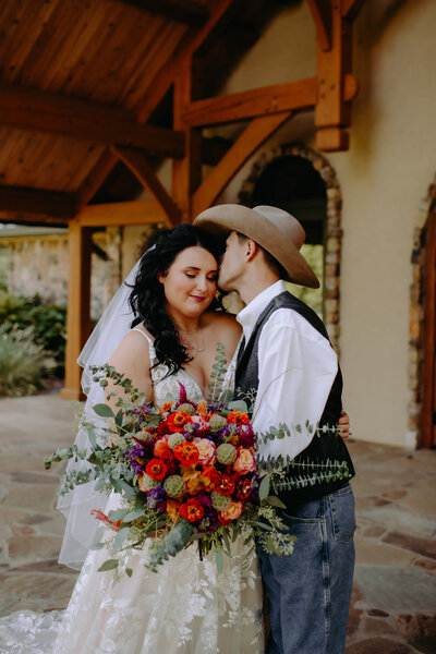 groom kissing his bride at their wedding at 81 Ranch venue