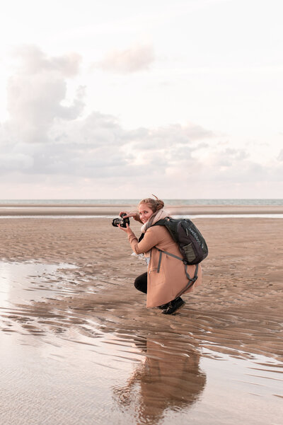Lianne Kastelein, fotograaf gespecialiseerd in gezinsshoots, poseert op het strand – actief in Alphen aan den Rijn en omstreken.