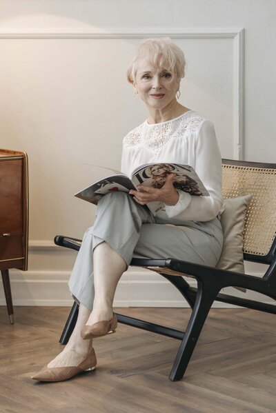 Senior woman with short hair sitting in waiting room with magazine