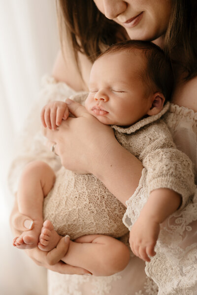 Photo of a Mom cuddling her baby close at a newborn photoshoot in Shrewsbury. The baby is wrapped in a fluffy blanket.