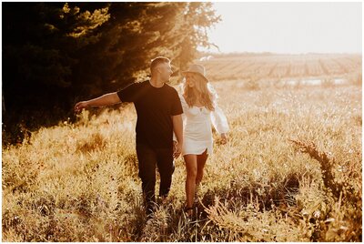 Couple holding hands and walking in a field during golden hour