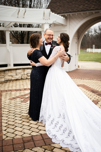 bride embracing her parents on her wedding day