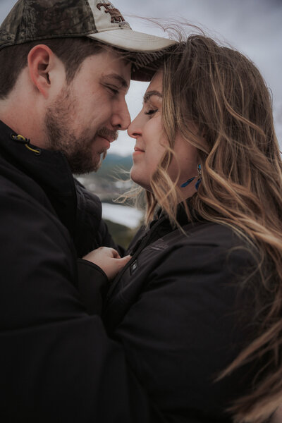 The photographer is crouched on a grassy hill with a lake behind her. She's holding a camera and looking to the right.