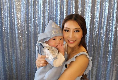 Woman with her baby standing in front of blue sequin backdrop for photos