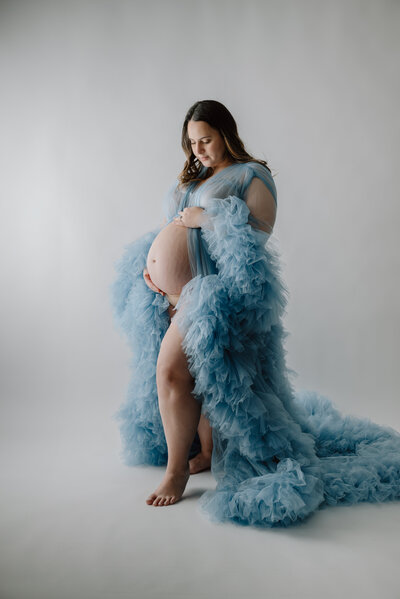 Glamour maternity photo of mom in blue fluffy robe in white studio in Annapolis Maryland.