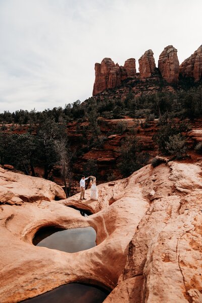 bride and groom walking in red rocks