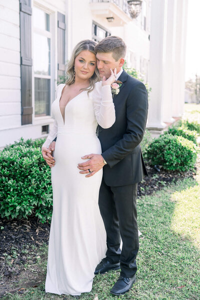 Groom embraces his bride outside a grand mansion. A timeless wedding portrait by Jackson Ms Wedding Photographer.