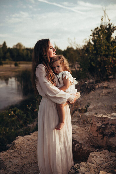 mother holding daughter by lake