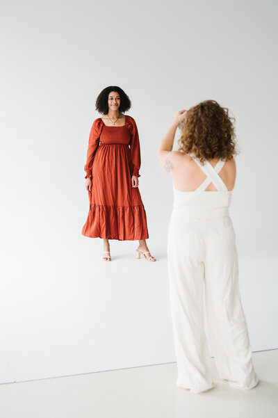 Photographer with red curly hair sits on the floor holding her camera