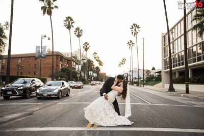 Groom dips his Bride in the middle of a busy intersection in Los Angeles and kisses her