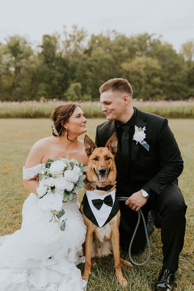 Bride and groom with their dog in a tuxedo.