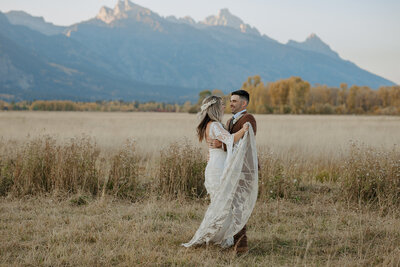 Couple looks at camera at sunset in Jackson Hole, Wyoming at Spring Creek Ranch