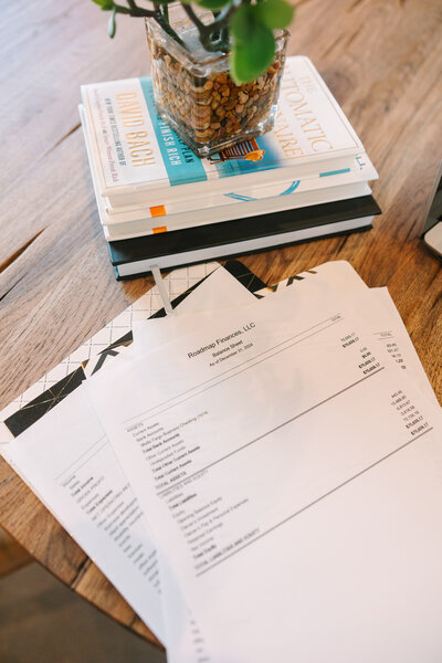 Stack of invoices sitting on a wood table next to a stack of books
