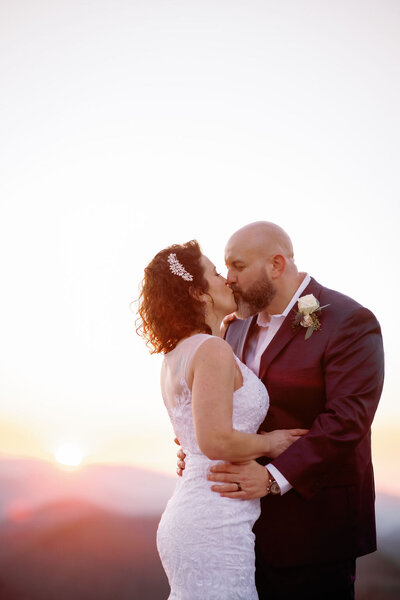 foothills elopement with groom holding his bride around the waist as she leans in to kiss him while they elope to Gatlinburg in the Smoky Mountains