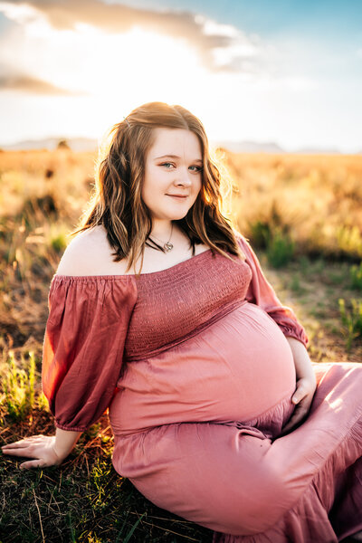 Mother sits on the grass on golden hour Colorado Springs  Maternity session