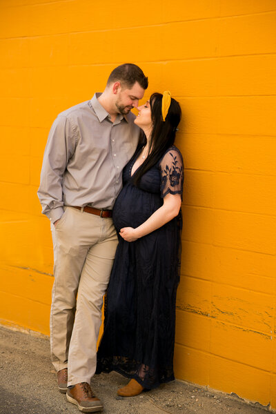 Photo of expecting parents in front of orange wall | Maternity Session
