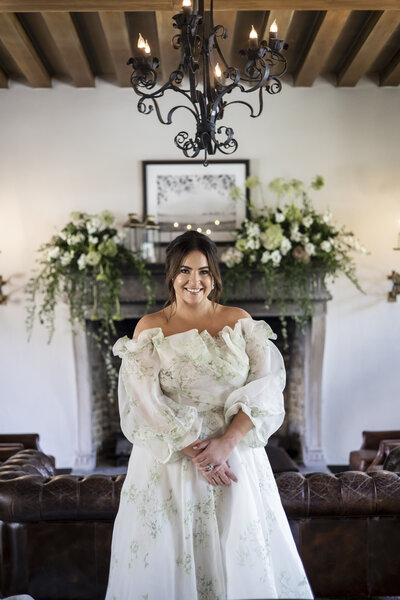 Bride standing in front of fireplace smiling.