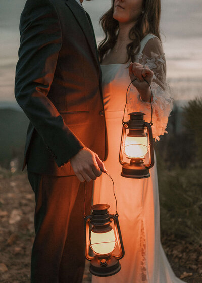 Detailed photo of bride and groom focusing on them holding lanterns