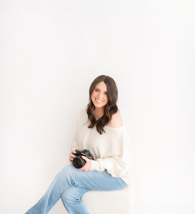 boston newborn photographer molly katherine poses holding camera during studio headshot photoshoot
