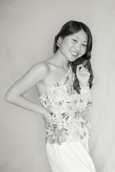 laughing bride in strapless wedding dress with bow standing on white porch with bouquet at Mattie's Austin