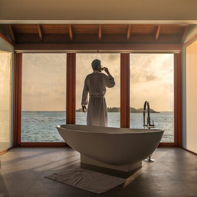 Freestanding soaking tub in an overwater bungalow in the Maldives overlooking the turquoise sea
