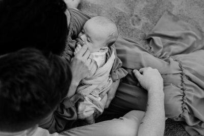 Black and white photo of mom holding baby boy with pacifier.