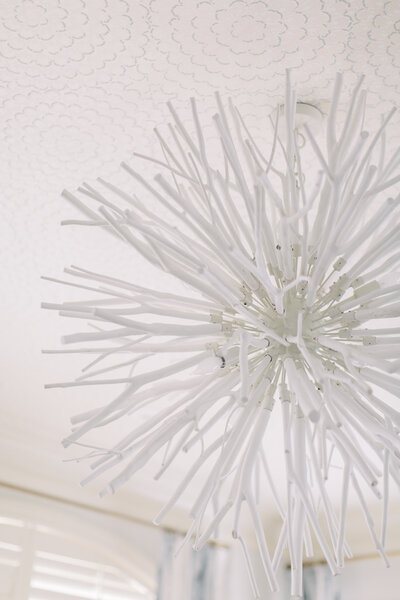 Modern white chandelier with intricate sculptural details, adding a striking focal point to the ceiling design.