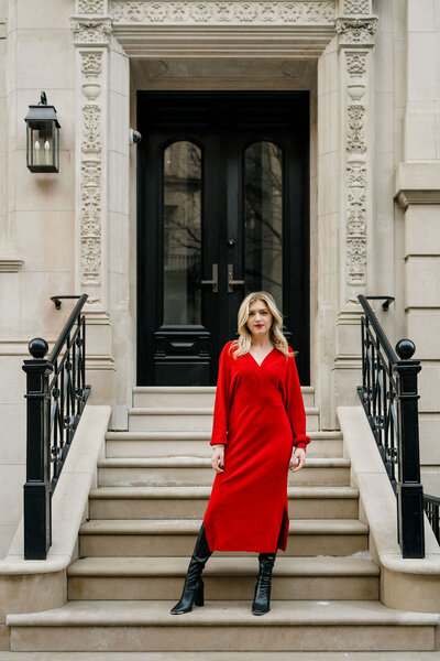 woman standing on the steps in front of a building in a long red dress