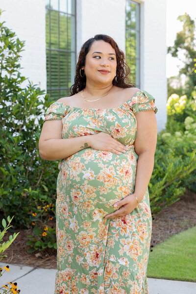 Pregnant woman holding belly outdoors at park in Phenix City Alabama