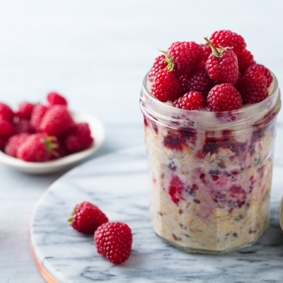 A jar of overnight oats topped with fresh raspberries, a nutritious and delicious breakfast option.