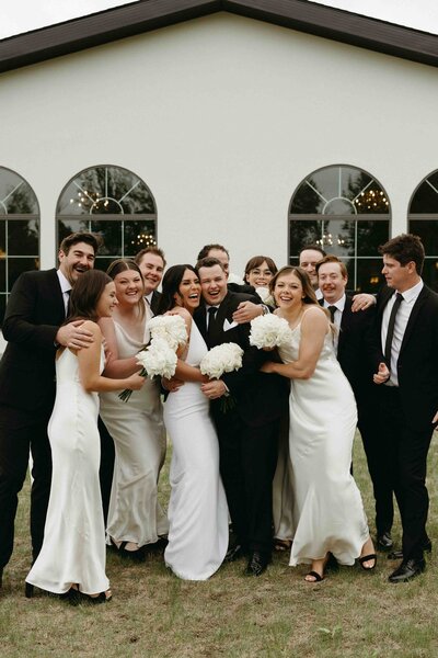 Bride and groom with bridesmaids and groomsmen outside a modern Alberta venue on wedding day